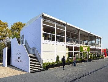 Two story tent F1 Paddock Club exterior with white PADDOCK branded stair wall