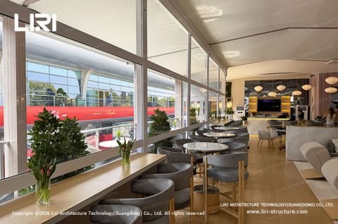Two story tent F1 Paddock Club upper floor trackside lounge with race car passing outside