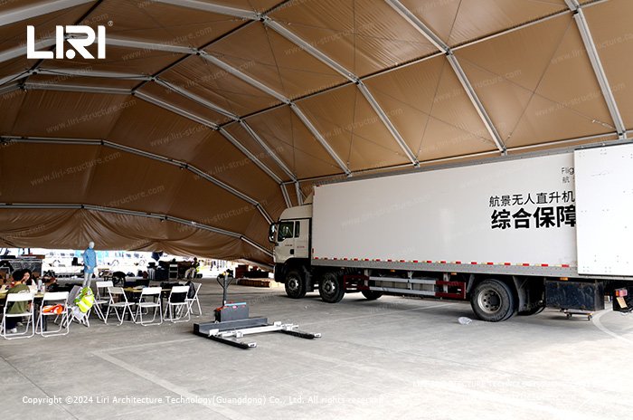 Inside an aluminum helicopter hangar protecting a support vehicle