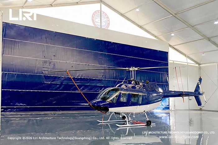 Helicopter parked inside a modular aircraft hangar with flexible door panels