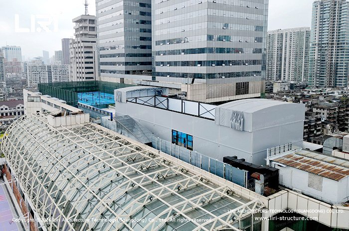 Urban rooftop pickleball court retractable roof structure beside high-rise buildings