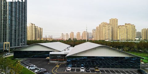 Curved-roof indoor badminton hall exterior in an urban sports complex