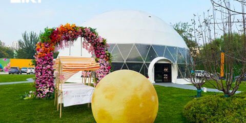 Geodesic dome tent at an outdoor brand pop-up event with a floral entrance