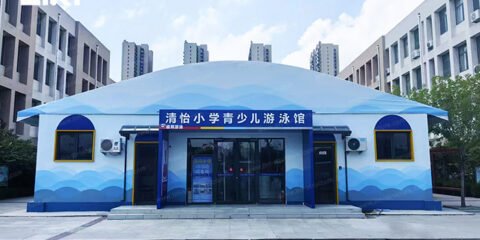 Front exterior of a school youth swimming pool tent with a curved membrane roof