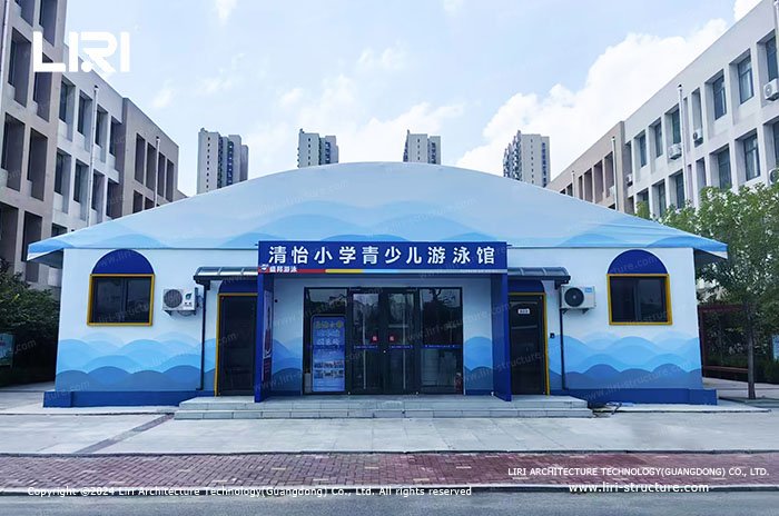Front exterior of a school youth swimming pool tent with a curved membrane roof
