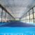 Indoor tennis court with a high truss roof and daylight entering through sidewall panels