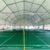 Green badminton courts and nets beneath a white fabric roof with raised side curtains